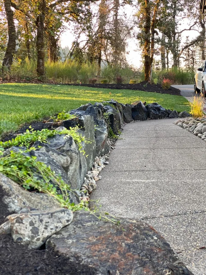 Curved paved path beside a low natural-stone retaining wall